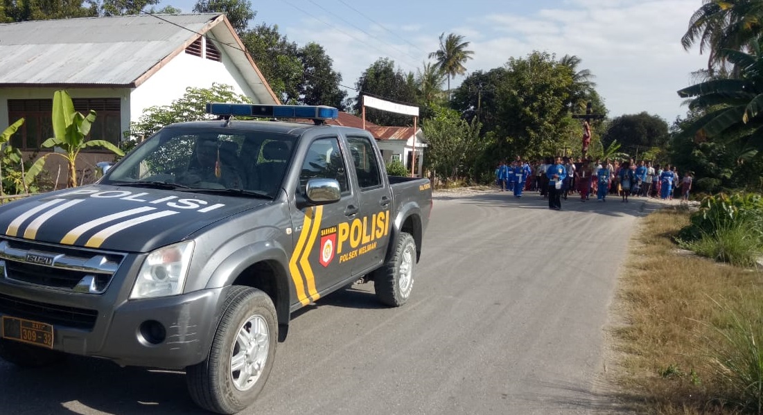 Di Jalan Raya Besitaek, Polsek Weliman Jaga Penerimaan Salib Suci dari Paroki St.Yohanes Rosul